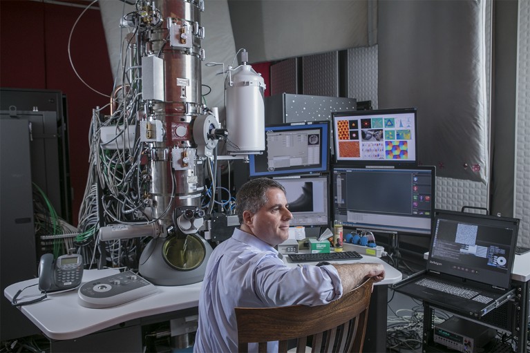 David Muller seated in front of his electron microscope in his lab at Cornell University