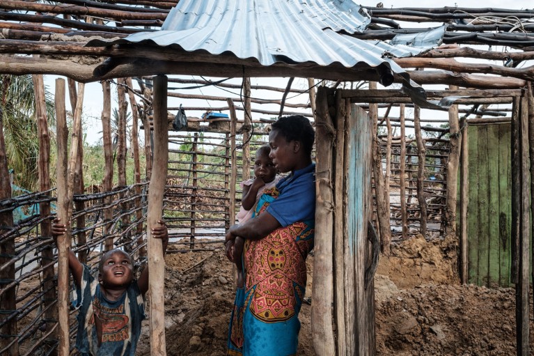 A woman stands with her children in her home which was destroyed by the winds of cyclone Idai