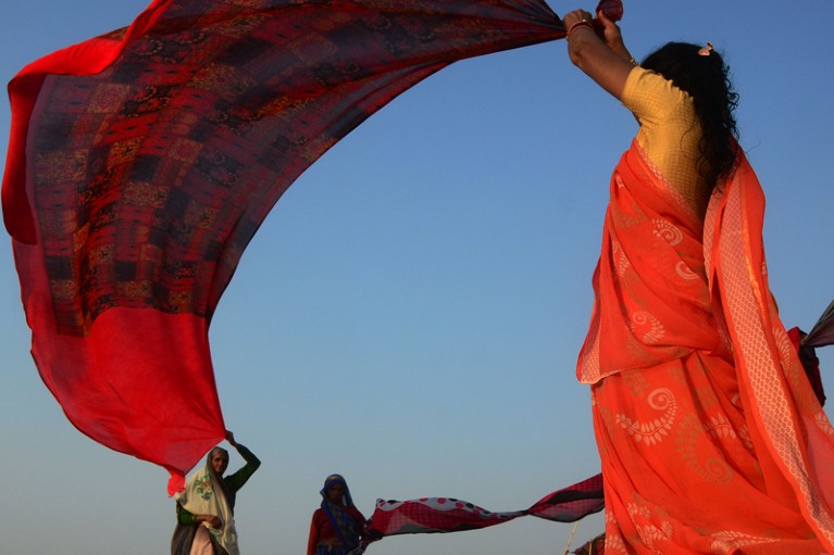 Indian women dry their sarees after taking a holy dip at Ganges river during a hot day in Allahabad