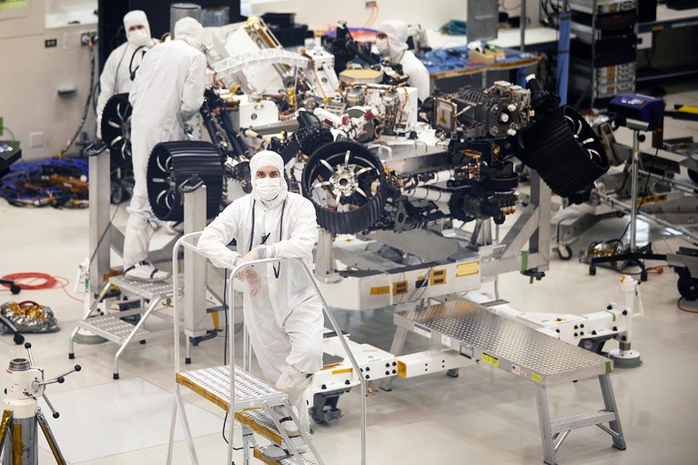 Workers wearing white protective suits in a clean room at the JPL NASA lab