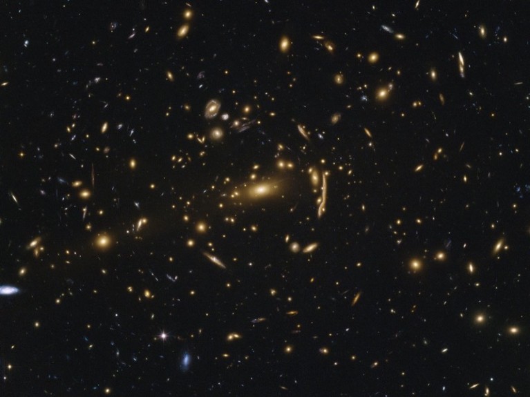 Yellow, white and blue galaxies against a black background.
