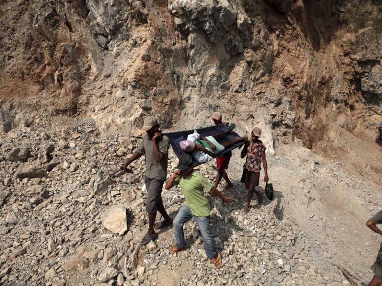 Men carry a patient on stretcher through a mountain pass in Benighat, Dhading, Nepal. 2010.