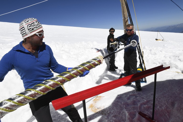 Members of the "Ice Memory project" extract an ice core piece out of a drill machine