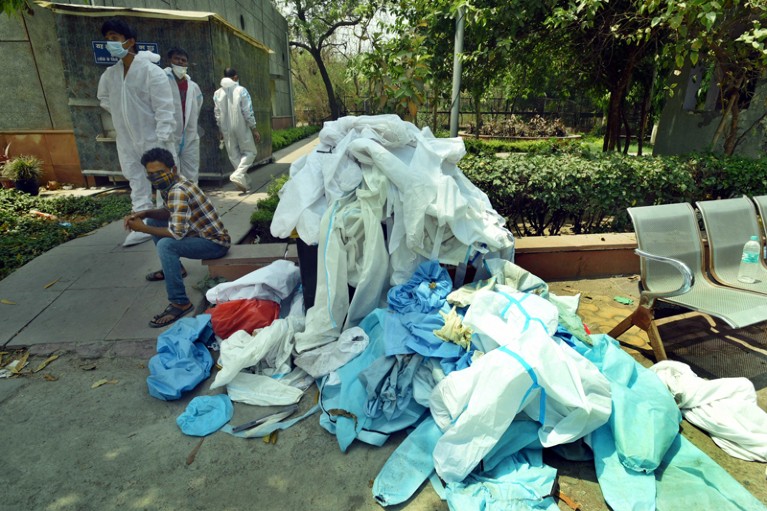 A pile of discarded PPE kits and other waste spilling out of a dustbin