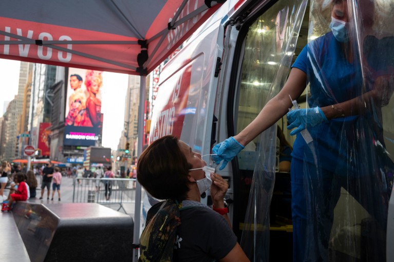 A man undergoes a nasal swab by a health care worker at a mobile COVID-19 testing site in Manhattan