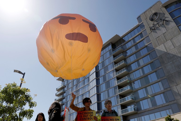 Demonstrators holds a inflatable angry emoji during a protest in California.