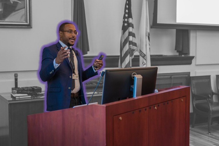 Frankie Heyward, surrounded by a purple outline, presents during a symposium.