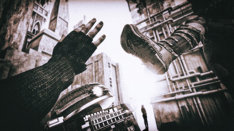 A gloved hand reaches up to stop a booted foot as it closes in to kick a small robot