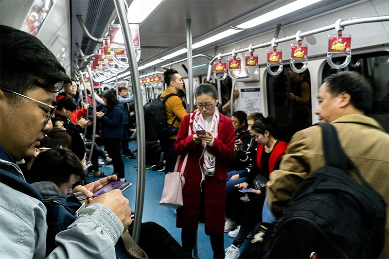 People are watching smartphones on a busy subway car in China