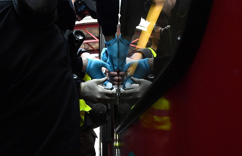 Police officers work to remove the hand of a protester who has super glued his hand to a train window