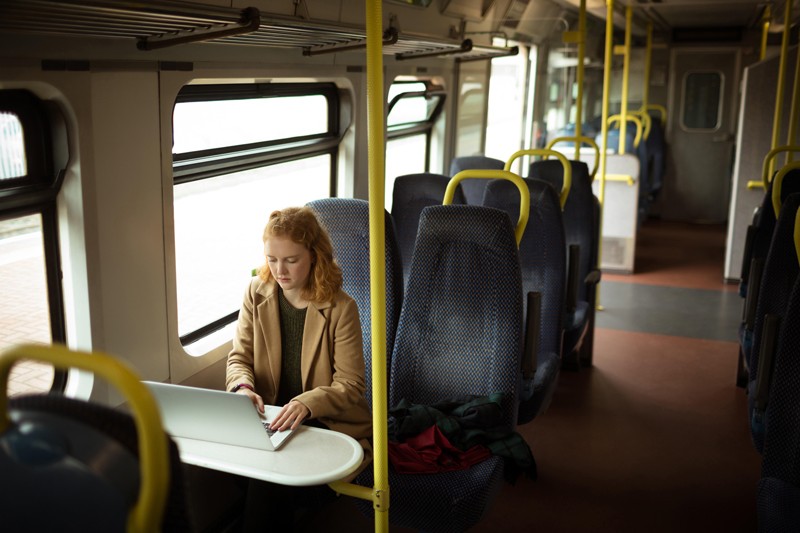 Young red-haired woman using her laptop in a train