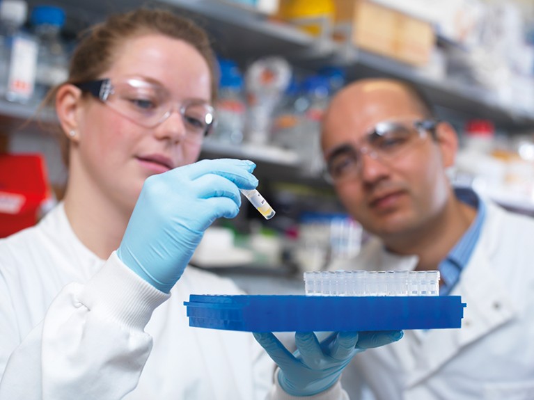 Two researchers in a lab examine a vial