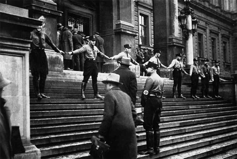 Nazi members link hands at the entrance of UNiv. Vienna to prevent Jewish people from entering. 1938.