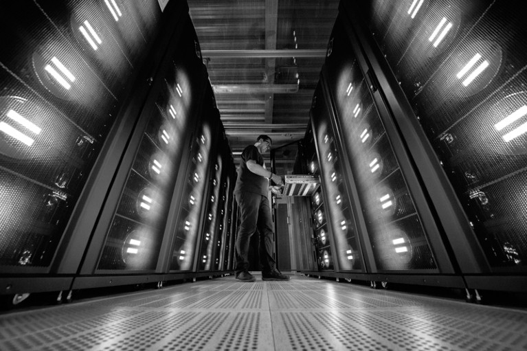 A worker poses next to a supercomputer