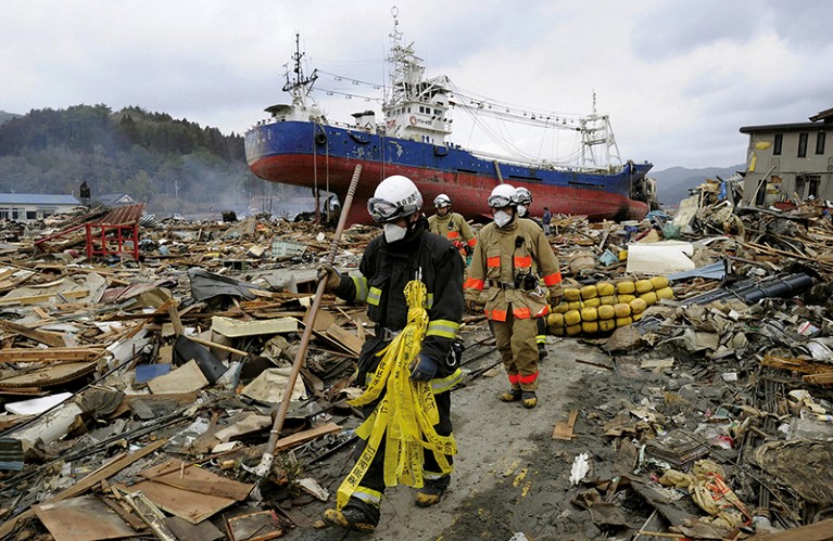Emergency workers walking through earthquake wreckage in Kesennuma, northeastern Japan