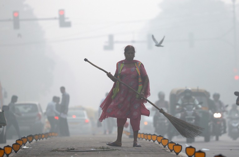 A street cleaner works in heavy smog in Delhi
