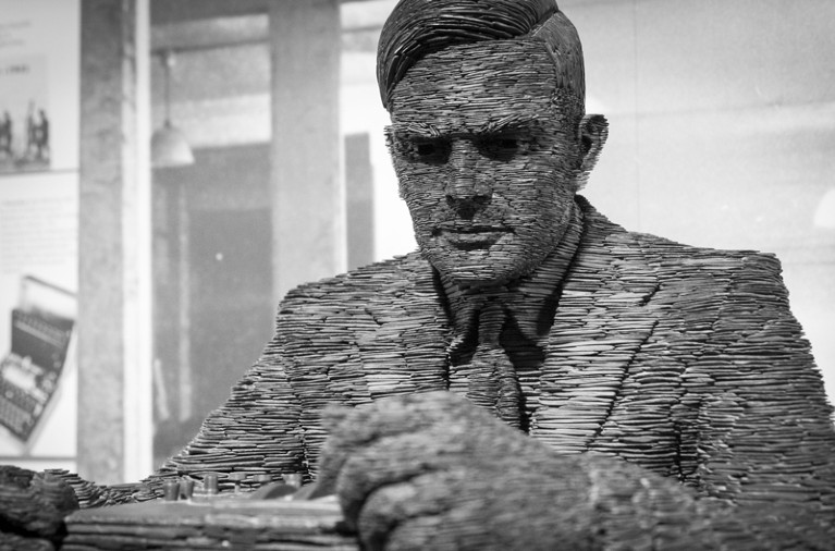 Statue of Alan Turing made of layers of stacked slate, shown from the chest up.