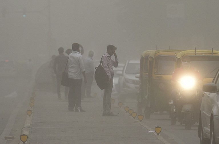 A man shields his eyes as he crosses a road during a sudden dust storm on the 2nd May in New Delhi, India.
