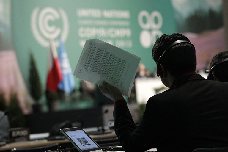 A man holds documents as he listens to statements of delegates during COP19 in Warsaw in 2013.