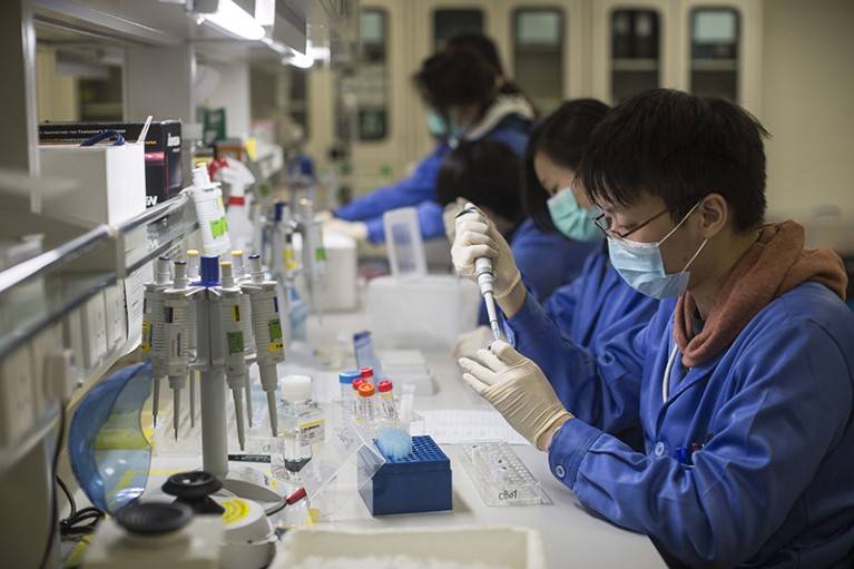 A team of scientists works at a lab bench
