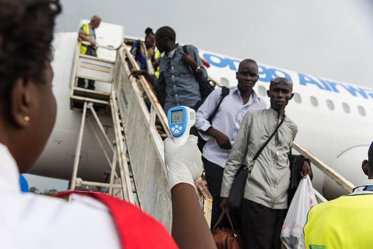 A health official uses a thermometer to measure the temperature of passengers disembarking a plane in DRC, May 2018