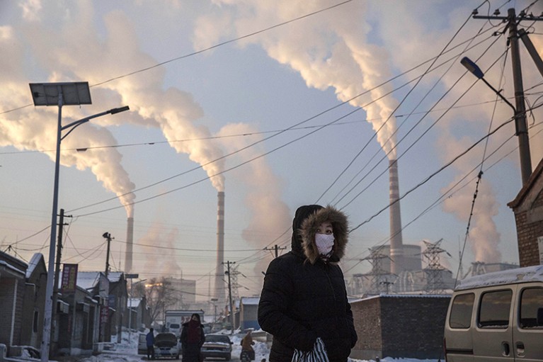 A woman walks near a coal-fired power station in Shanxi, China