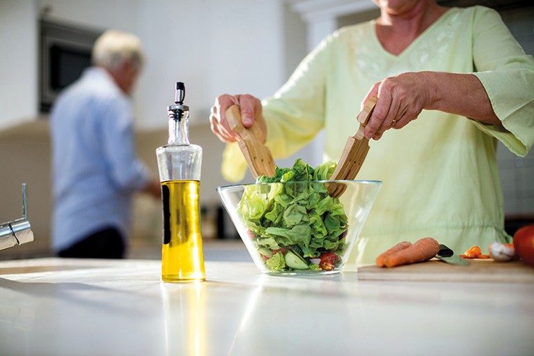 An older woman prepares a salad.