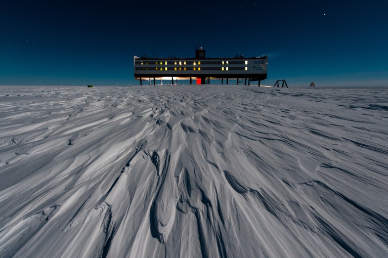 Neumayer Station III seen lit up at night on a snowy plain