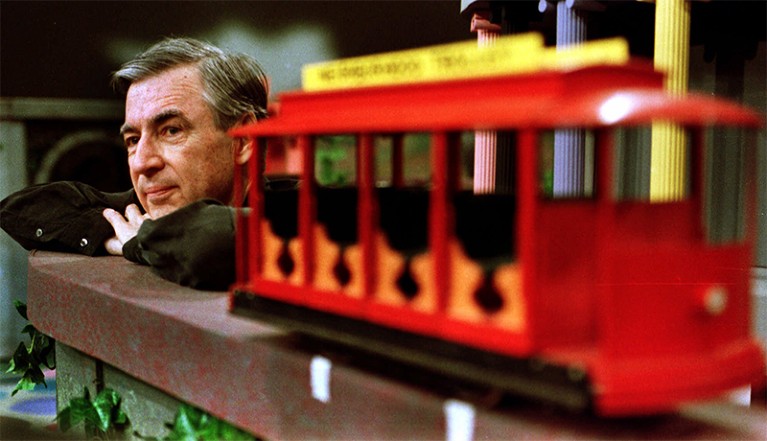 Mr Rogers(l) gazes into the distance during a pause in filming.The red neighbourhood trolley is in the foreground(r)
