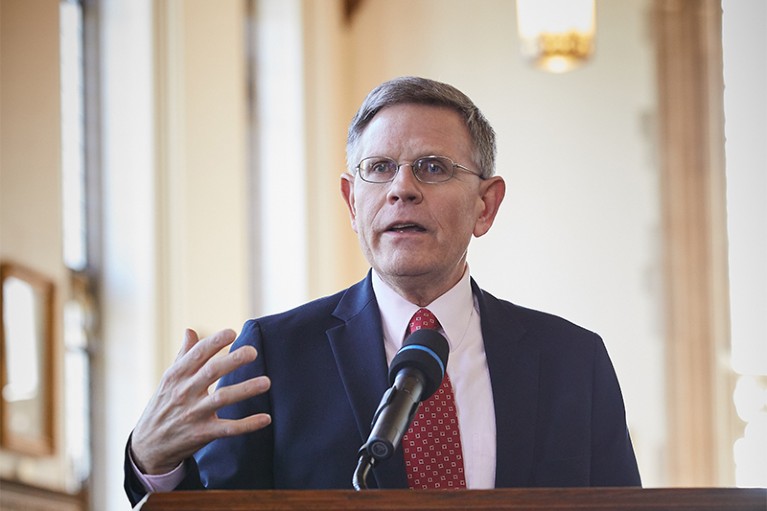 Droegemeier gestures as he speaks into a microphone on a podium in the Bizzell Library at Univ. Oaklahoma