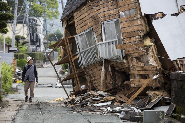 An earthquake survivor is seen through the wreckage of houses