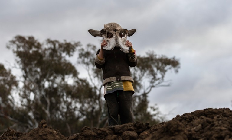 A boy holds an animal skull on his family's farm in New South Wales, Australia