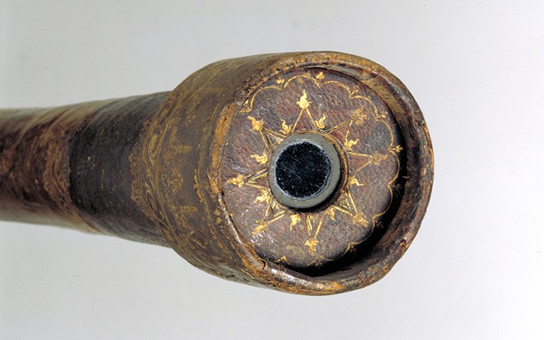 Close up image of Galileo's telescope. Astronomical symbols are picked out in gold decoration.