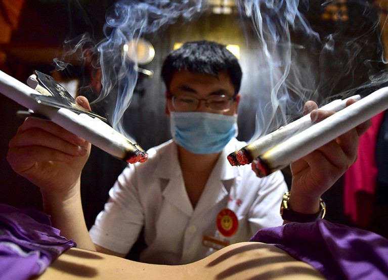 A practitioner of traditional Chinese medicine treats a patient