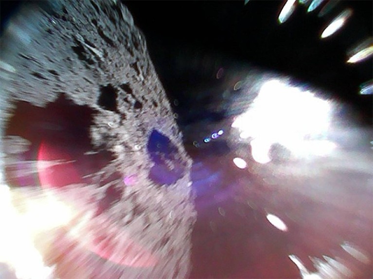 Blurred photo from Rover-1A taken during a hop showing asteroid Ryugu to the left. The bright white region is due to sunlight.