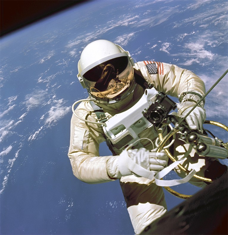 Ed White, astronaut, can be seen in space holding equipment. Below him is Earth.