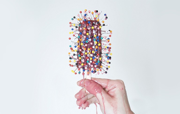 Iced lolly covered in pins dripping on to a hand