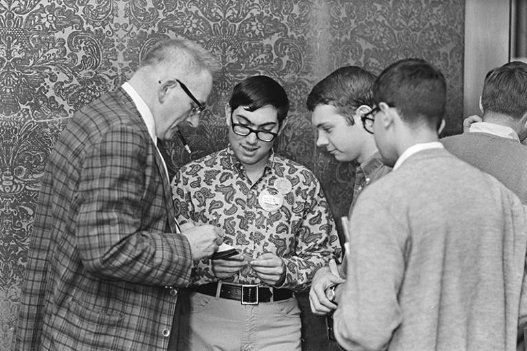 John W. Campbell (l) signs autographs for three fans .