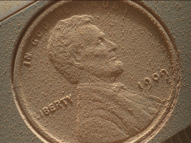A coin loaded onto the Mars Curiosity rover covered in dust
