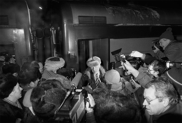 Sakharov (c) in a woolly hat talks to a swarm of reporters at Yaroslavl terminus