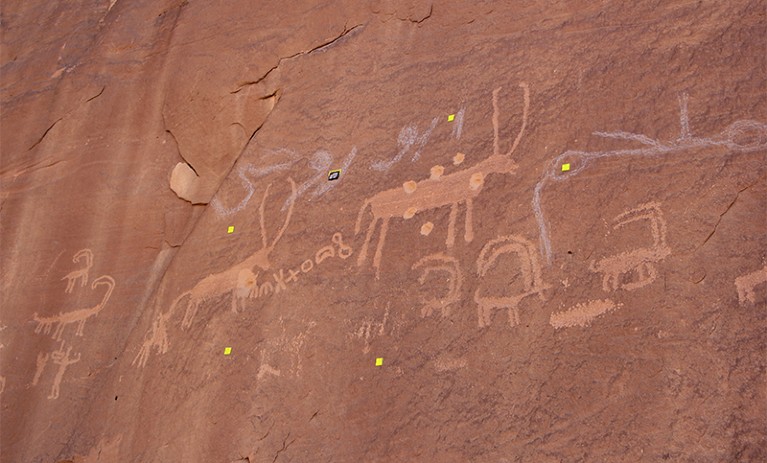 Rock paintings of antelope like animals and symbols scattered with bullet holes + damage