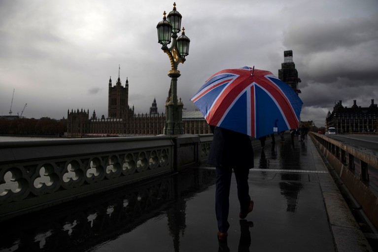 A man carries a Union Flag umbrella as he walks over Westminster Bridge