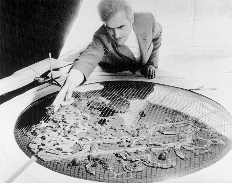 Frei Otto leans over his arctic city model, pointing out an area of interest