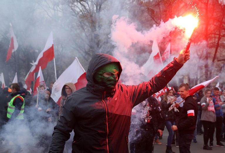 A protester in Poland holds a flare.