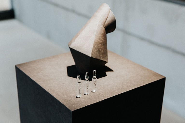 An angular speculative design of a black steel inhaler on a plinth with three labelled glass vials in front of it. Emilia Tikka.
