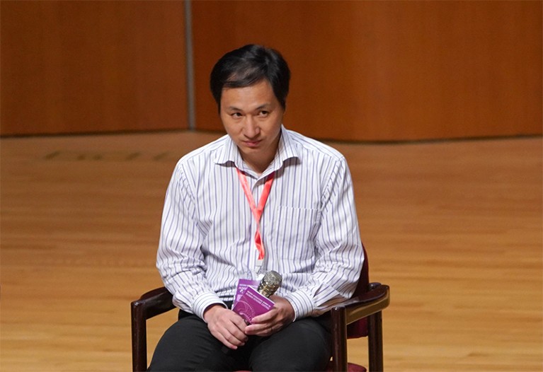 He Jiankui, seated, looks up as he answers questions during his presentation at the human genome editing summit on 28th November