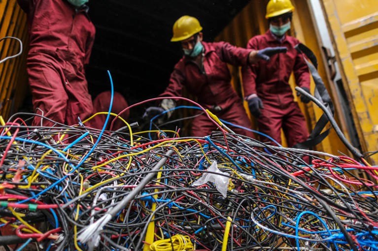 Workers offload cables at an electric recycling facility