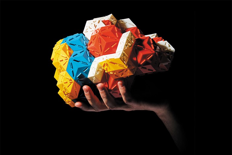 A hand holding a colourful quasicrystal model. Simon and Schuster.