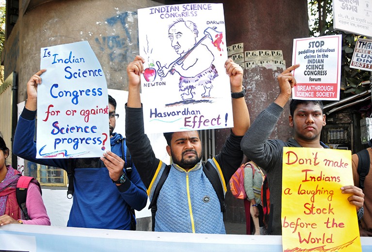People hold signs to protest comments made at the Indian Science Congress