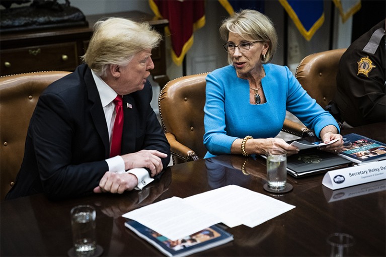 Donald Trump seated next to Betsy DeVos at a meeting.